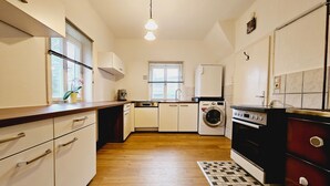 Cocina compacta con lavadora, horno y un pequeño comedor con ventana.