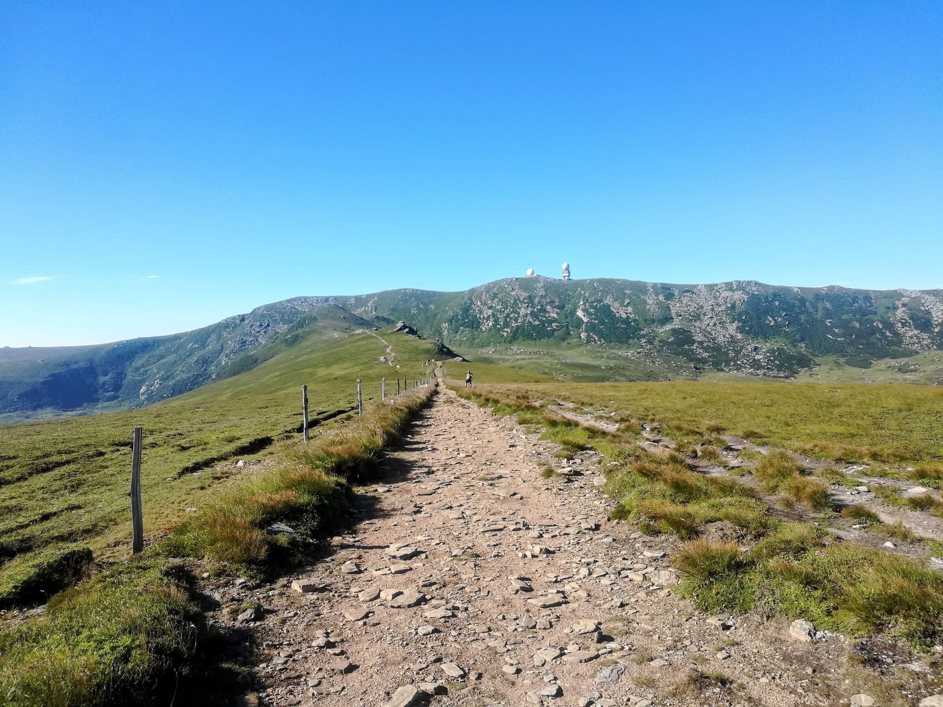 En grussti der fører hen til et bjerg under en klar himmel.