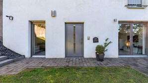 A modern building with a glass door, a small window, and a potted plant. - Holiday Apartment 'Eifel im Herzen' with Private Terrace, Garden & Wi-Fi (Hambuch)