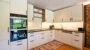 A modern kitchen with white cabinets, a built-in oven, and a coffee machine. - Apartment in Tyrol near Kitzbühel (Jochberg in Tirol)