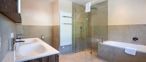 A modern bathroom with a large bathtub, a glass-enclosed shower, and a wooden vanity.