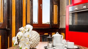 A dining table with white orchids, a coffee pot, cups, and a tray.