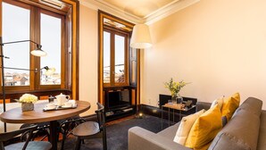 A cozy living room with a fireplace, a dining table with chairs, and a sofa with cushions. - Beach studio nearby market in Oporto (Oporto)