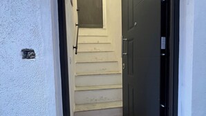 A narrow hallway with a wooden floor, a white wall, and a black door at the end. - Kensia house - historic center - central station (Palermo)