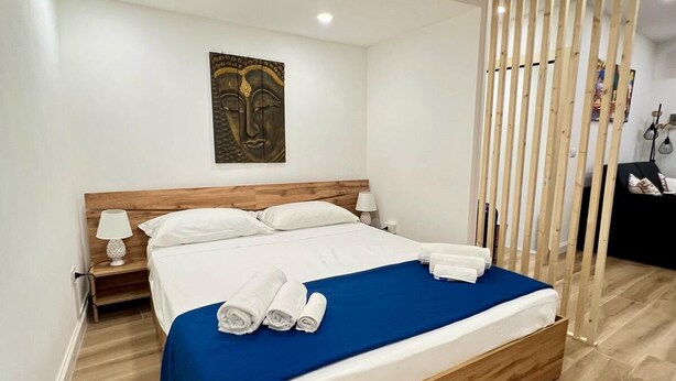 A modern hotel room with a wooden bed, white linens, and a blue accent. - Kensia house - historic center - central station (Palermo)