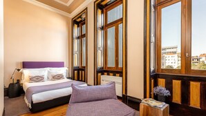 A bedroom with a bed, a sofa, a window, and a radiator.