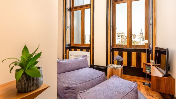 A room with a large window, a sofa, a small table, and a television.