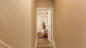 A narrow hallway with a carpeted floor and a door leading to a room with a desk and chair. - Charming 1-Bedroom Apartment in Oporto (Oporto)