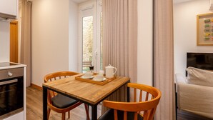 A compact kitchen with a dining area, a TV, and a window with curtains. - Charming 1-Bedroom Apartment in Oporto (Oporto)