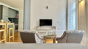 A modern living room with a sofa, a coffee table, and a television. - Cozy Porto studio with balcony (Oporto)