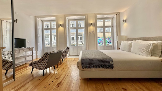 A bedroom with a bed, a TV, a desk, and two chairs. - Cozy Porto studio with balcony (Oporto)