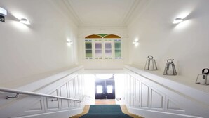 A staircase with white walls, a green carpet, and a view of a room with a door at the top.