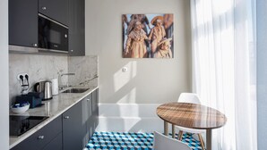 A modern kitchen with a microwave, sink, and a painting of figures on the wall.