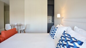 Ein Hotelzimmer mit Bett, einem kleinen Tisch mit Stühlen, einer Küchenzeile und einer Tür zu einem anderen Raum.