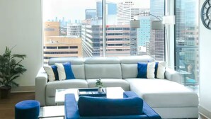 Una sala moderna con un amplio sofá modular, una mesa de centro y una planta en maceta.