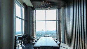 Una sala de conferencias moderna con una gran mesa, sillas y vistas a un horizonte urbano a través de amplios ventanales.