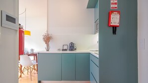 A modern kitchen with teal cabinets, a coffee machine, and a vase with dried flowers. - Charming studio, ideal for smaller groups (Oporto)