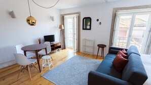 Ein modernes Wohnzimmer mit einer Couch, einem Esstisch, Stühlen und einem Fernseher.