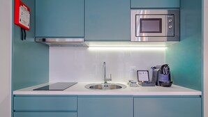 Eine moderne Küche mit einer Edelstahl-Spüle, einer eingebauten Mikrowelle und einer Kaffeemaschine.
