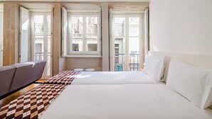 Ein Hotelzimmer mit einem großen Bett, einer Couch und einem Fenster mit Blick ins Freie.