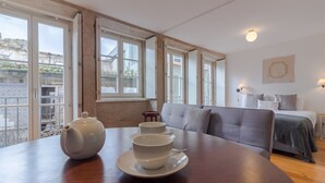 Una habitación con una mesa de comedor, dos teteras blancas, un sofá y una cama.