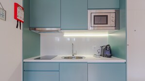 Una cocina moderna con gabinetes color turquesa, un lavamanos de acero inoxidable y un microondas.