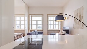 A modern kitchen with a central island, a dining table, and a sofa. - Stylish Porto studio with city views (Oporto)