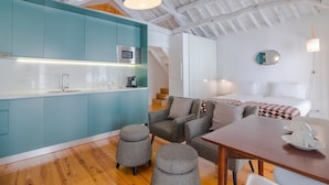 Una cocina moderna con armarios color turquesa, una mesa de comedor de madera y una escalera que conduce a un dormitorio con cama y mesita de noche.