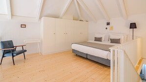 A bedroom with a bed, a chair, a wardrobe, and a desk.