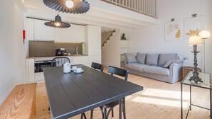 A modern interior with a dining table, chairs, a sofa, and a staircase leading to an upper level.