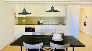 A compact kitchen with two pendant lights, a coffee machine, and a sink. - Trendy Studio in the Heart of Porto (Oporto)