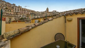 A rooftop terrace with a view of a historic town, a small table, and a door. - Nice home in Modica with WiFi (Modica)
