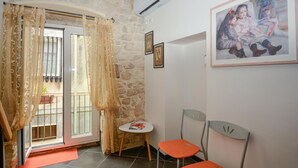 A room with a stone wall, a small table with a red mat, two orange chairs, and a door with a glass window. - Nice home in Modica with WiFi (Modica)