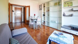 Un soggiorno con divano, un tavolo da pranzo con sedie, un angolo cottura con frigorifero e una libreria con ante in vetro.