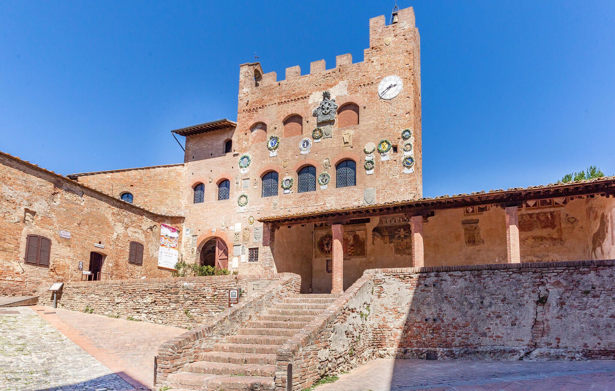 A historic building with a clock tower, arched windows, and a staircase leading to the entrance.