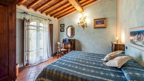 A bedroom with a wooden ceiling, a bed with a blue and white patterned bedspread, a dresser, a chair, and a chandelier. - Cozy home in Castelfiorentino (Castelfiorentino)