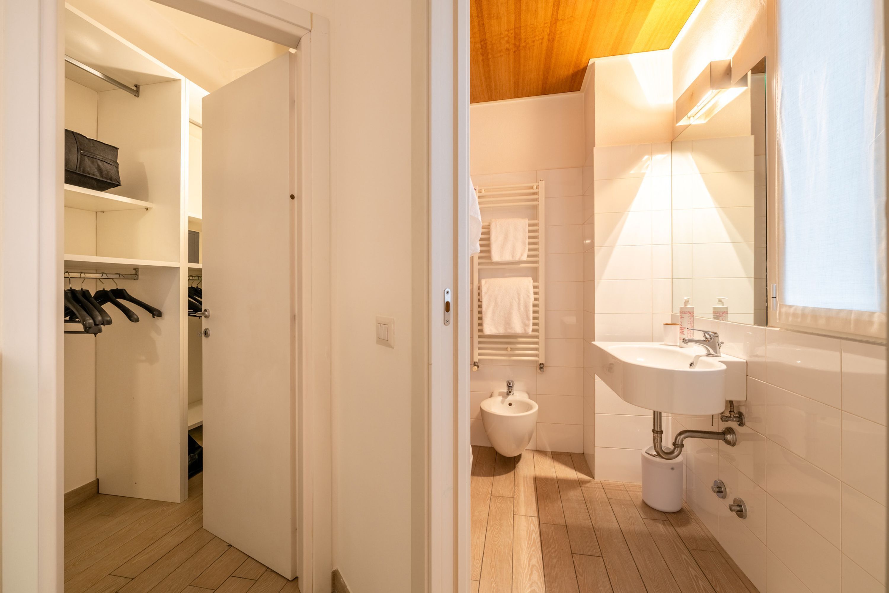 A modern bathroom with a bidet, white sink, and towel rack.