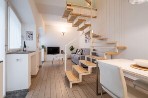 Ein moderner Wohnraum mit Küche, Essbereich und einer Treppe, die in eine obere Etage führt.