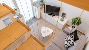 A modern living room with a sofa, a small white table, a TV, and a plant. - Viale Lecco 105 in Como (Como)