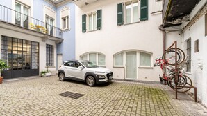 A white SUV parked in a cobblestone courtyard with a bicycle rack on the right. - Viale Lecco 105 in Como (Como)