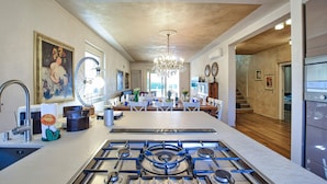A modern kitchen with a gas stove, dining area, and a staircase leading to another level.