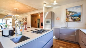 A modern kitchen with a central island, stainless steel appliances, and a wooden floor.