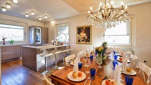 A modern kitchen with a central island, a dining area with a wooden table set for six, and a chandelier.