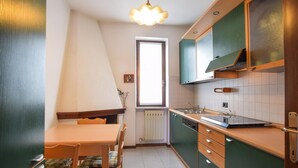 A compact kitchen with a dining table, chairs, and a window. - 2 bedroom beautiful home in Cisano di Bardolino (Cisano di Bardolino)
