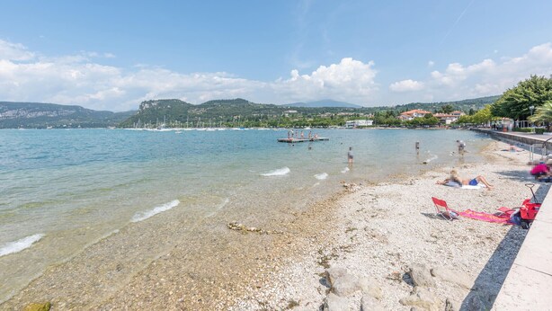 A pebble beach with clear water, boats, and a distant mountain range. - 2 bedroom beautiful home in Cisano di Bardolino (Cisano di Bardolino)