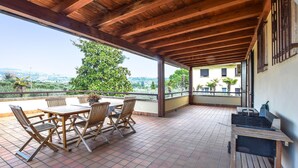 A covered patio with a wooden table and chairs, a grill, and a view of the city. - 2 bedroom beautiful home in Cisano di Bardolino (Cisano di Bardolino)
