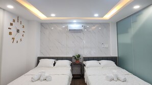 Una habitación de hotel moderna con dos camas, una pared de mármol, un reloj y un equipo de aire acondicionado.