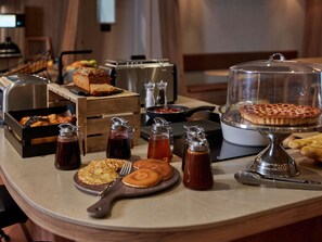 A breakfast buffet with various pastries, a hot griddle, and condiments. - Adagio Access Bordeaux Sud Pessac  (Pessac)