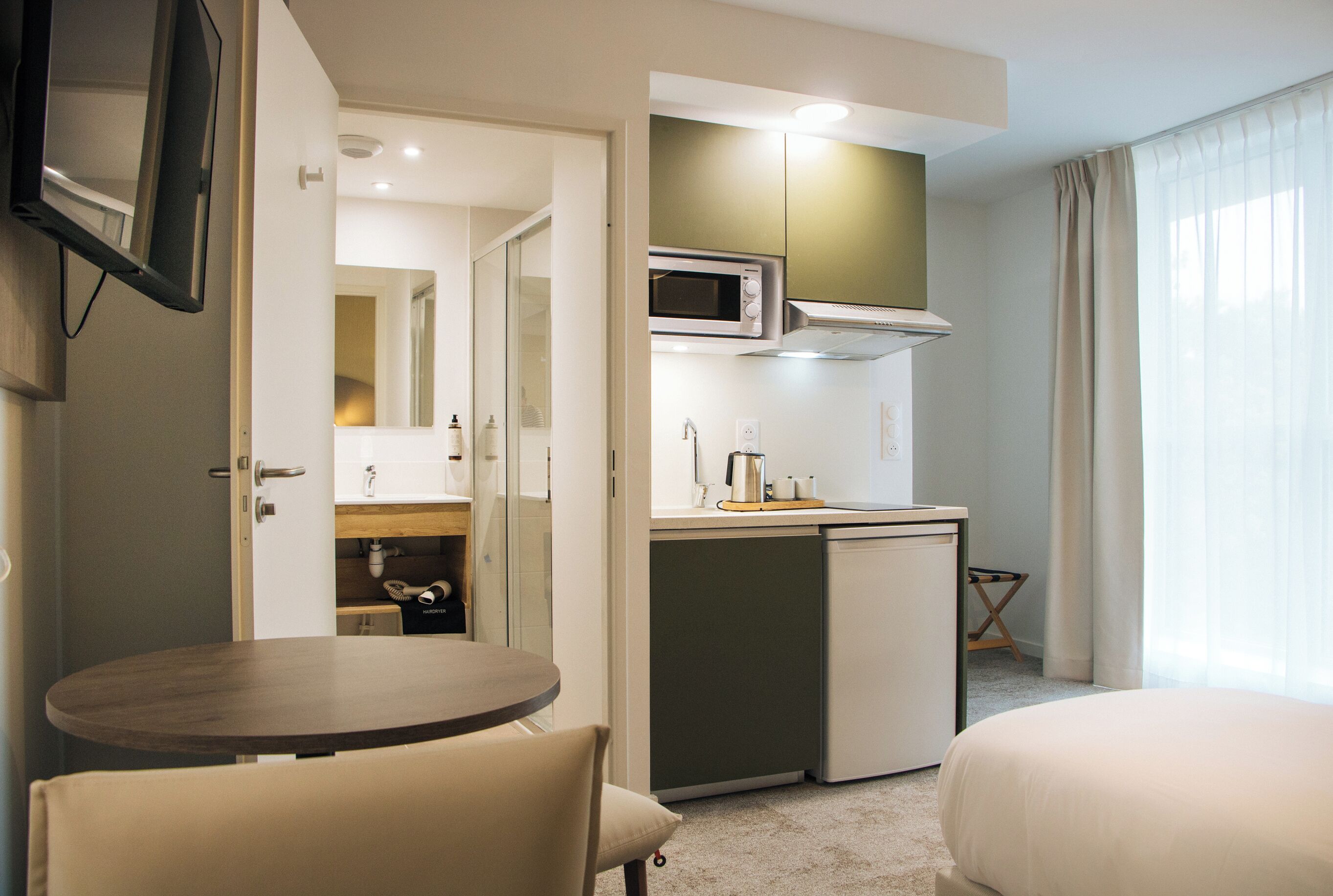 Une chambre d’hôtel compacte comprenant un coin cuisine, un espace repas et un lit.