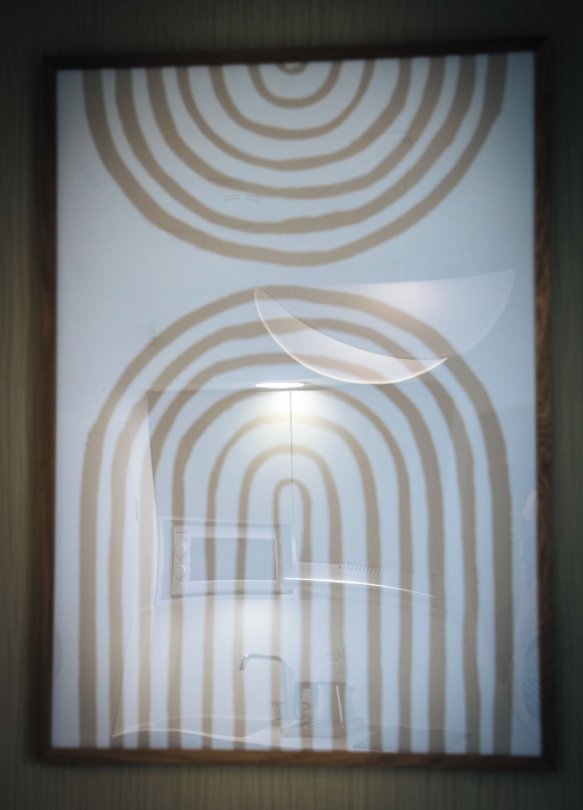 Une œuvre d’art encadrée, composée de cercles concentriques et d’un luminaire central.